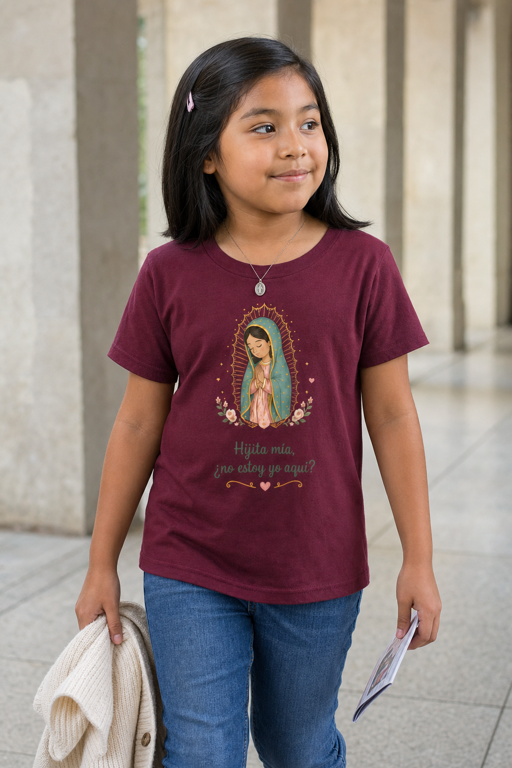 Girl wearing the Hijita Mía Guadalupe Girls T-Shirt in Maroon