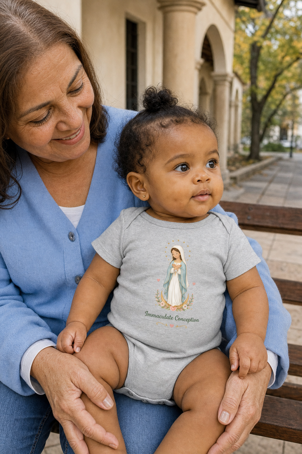 Baby girl wearing the Immaculate Conception Baby Bodysuit in Athletic Heather
