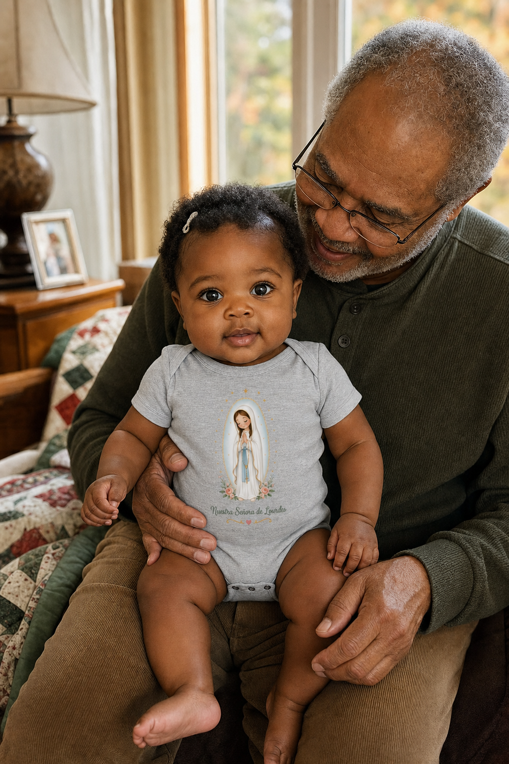 Baby girl wearing the Nuestra Señora de Lourdes Baby Bodysuit in Athletic Heather