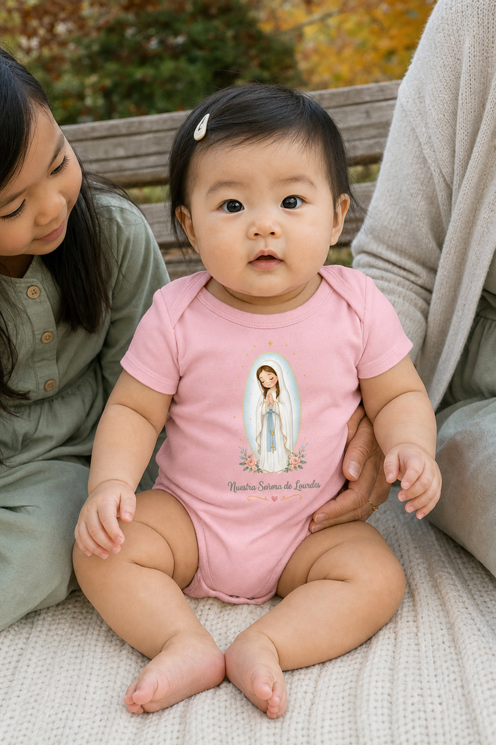 Baby girl wearing the Nuestra Señora de Lourdes Baby Bodysuit in Pink
