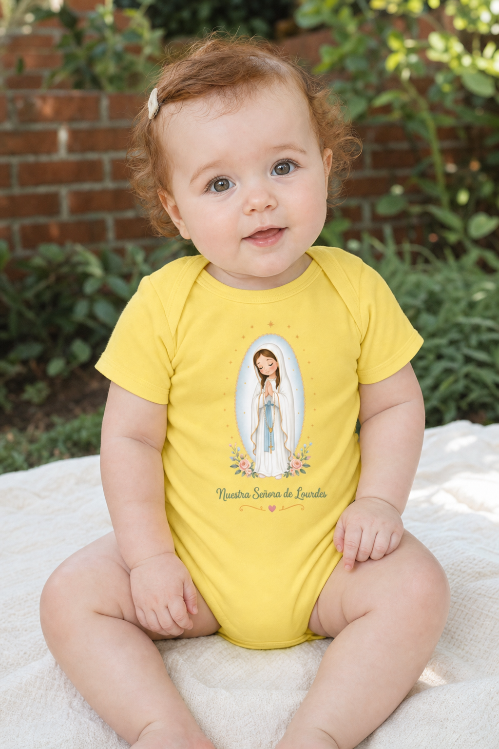 Baby girl wearing the Nuestra Señora de Lourdes Baby Bodysuit in Yellow