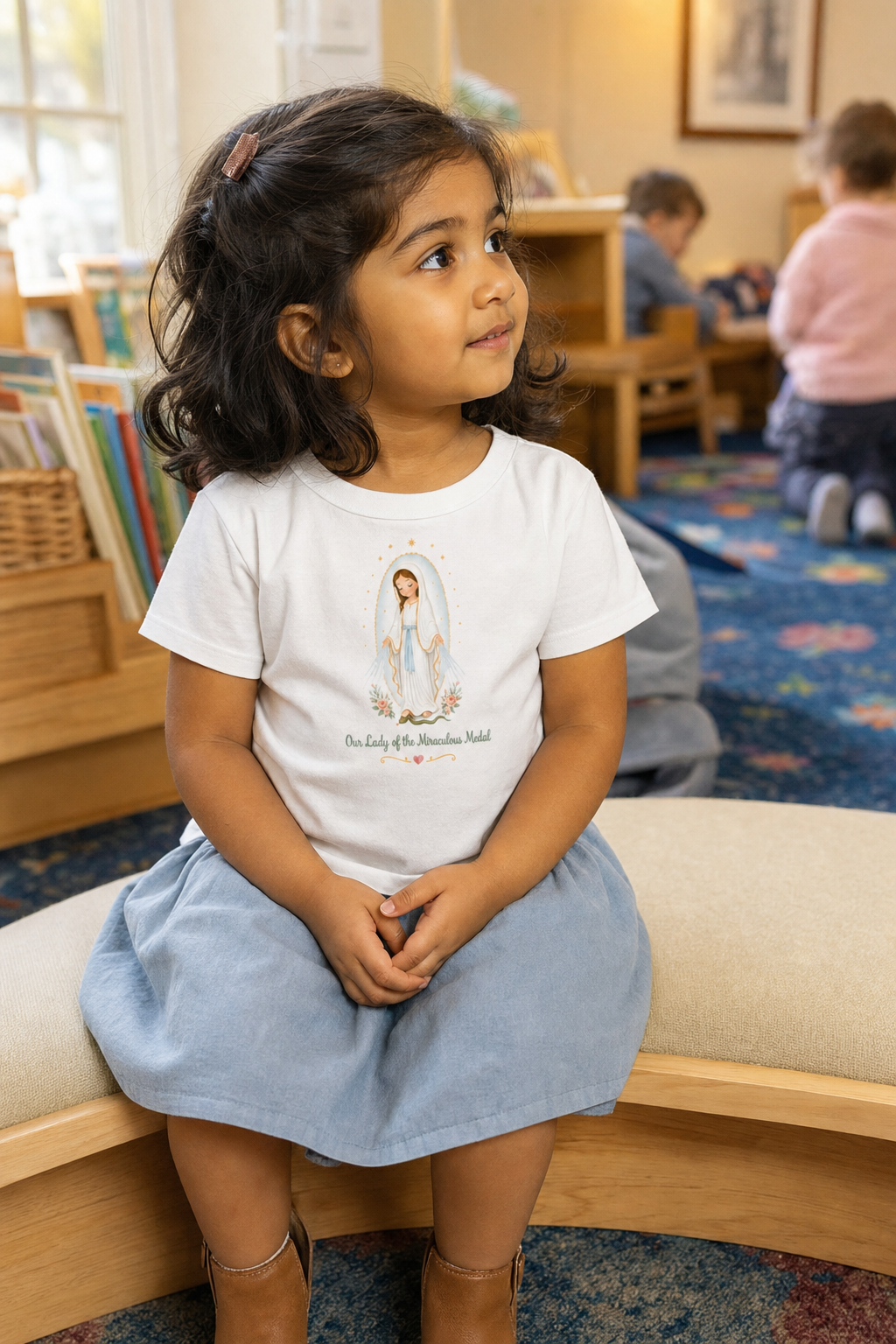 Little girl wearing the Our Lady of the Miraculous Medal Toddler T-Shirt in White
