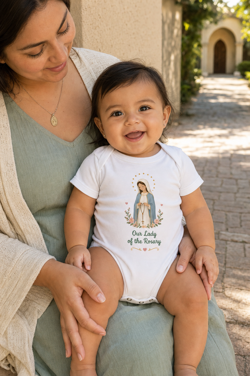 Baby girl wearing the Our Lady of the Rosary Baby Bodysuit in White