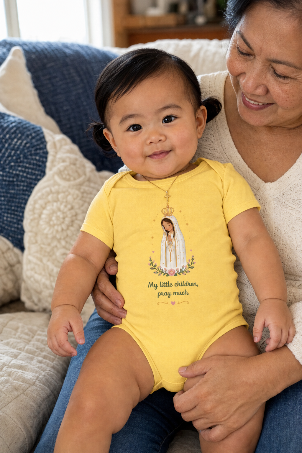 Baby girl wearing the Pray Much Fátima Baby Bodysuit in Yellow